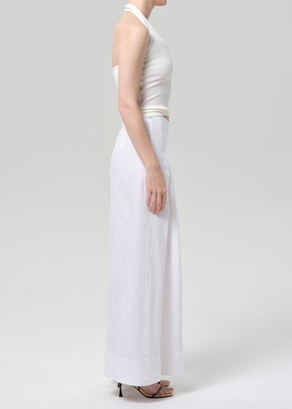 Woman wearing a white halter top and palazzo pants on a light gray background
