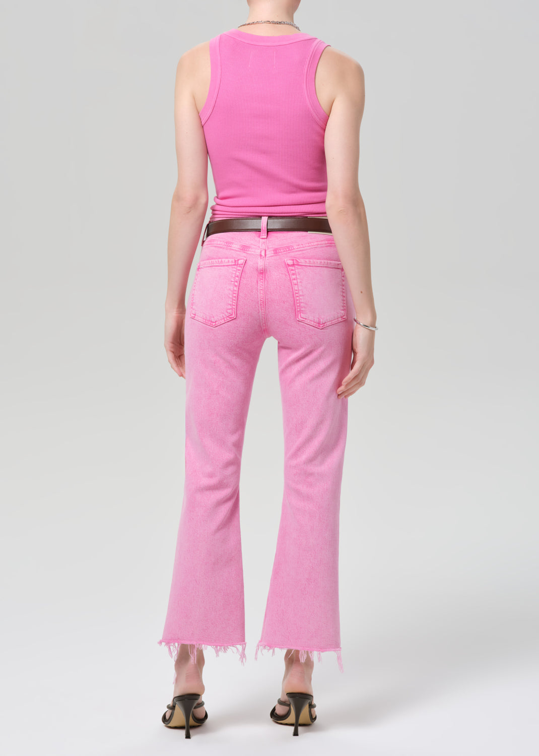 Person wearing a pink sleeveless top and pink jeans on a plain background
