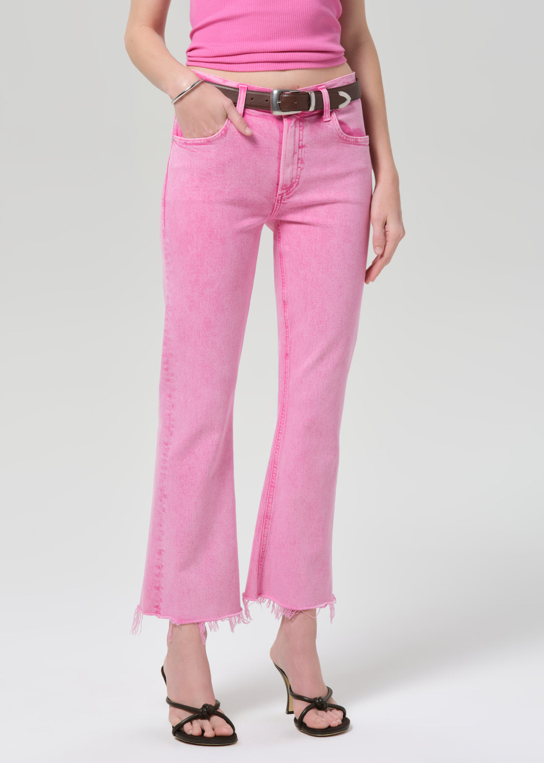 Person wearing a pink sleeveless top and pink jeans on a plain background