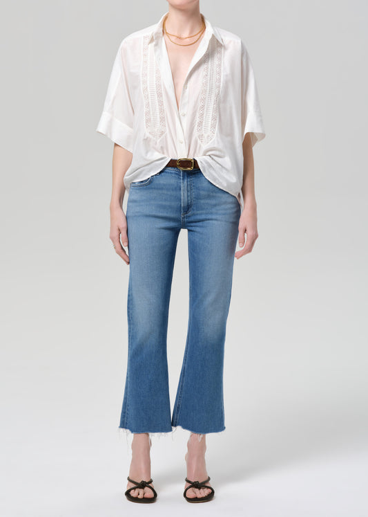 Person wearing a white shirt and blue jeans on a plain background