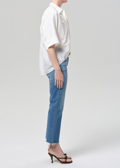 Person wearing a white shirt and blue jeans on a plain background