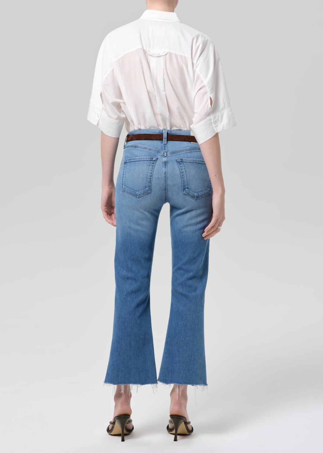 Person wearing a white shirt and blue jeans on a plain background