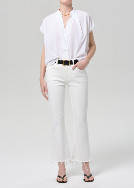 Person wearing a white shirt and white jeans on a plain background