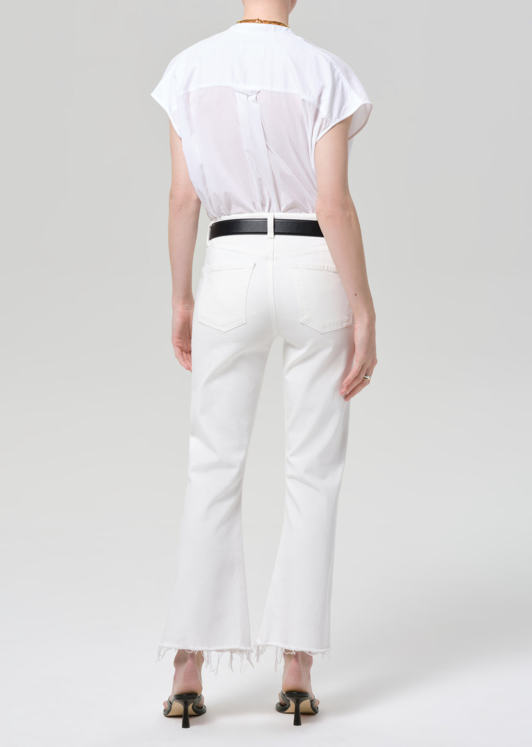 Person wearing a white shirt and white jeans on a plain background