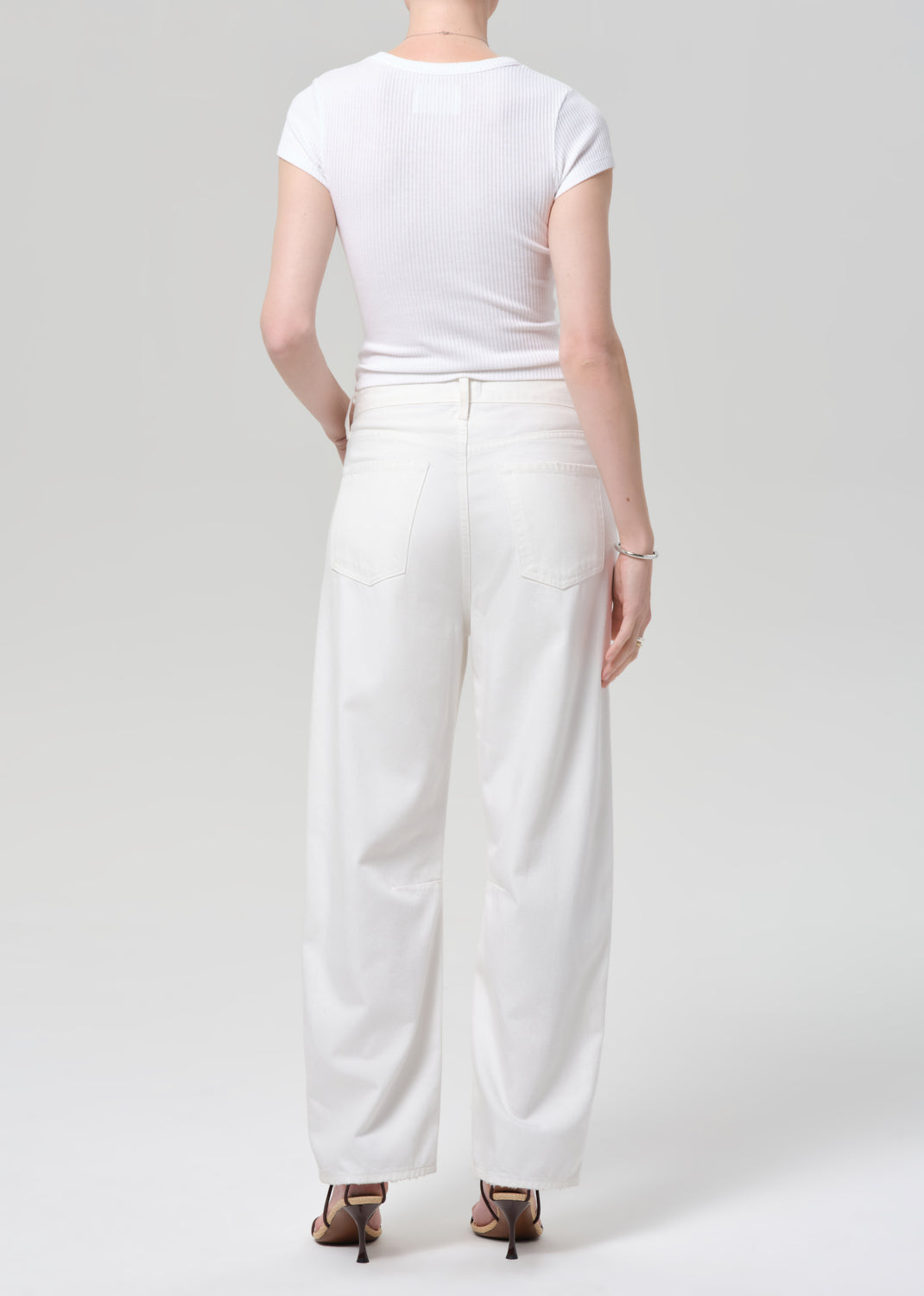 Person wearing a white t-shirt and wide-leg pants on a plain background