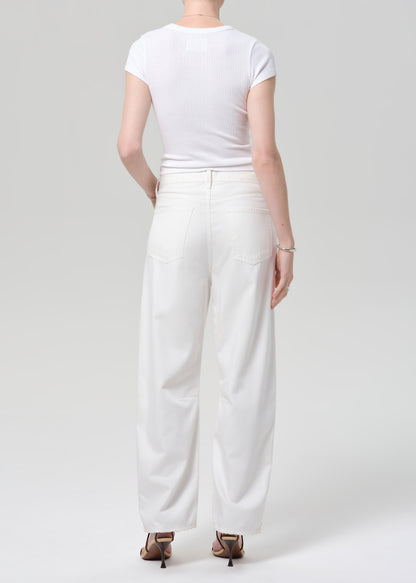 Person wearing a white t-shirt and wide-leg pants on a plain background
