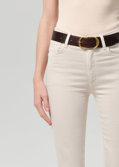 Person wearing a beige top and off-white pants with a belt on a light gray background