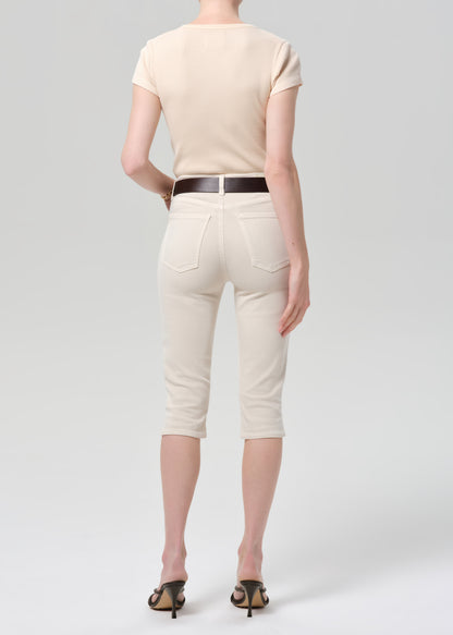 Person wearing a beige top and off-white pants with a belt on a light gray background