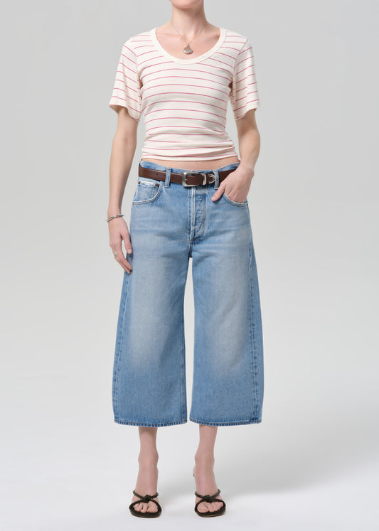 Person wearing a striped shirt and wide-leg jeans on a plain background