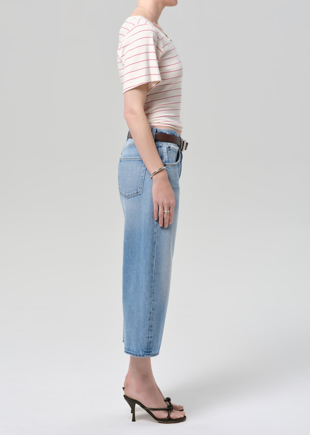 Person wearing a striped shirt and light blue jeans on a plain background