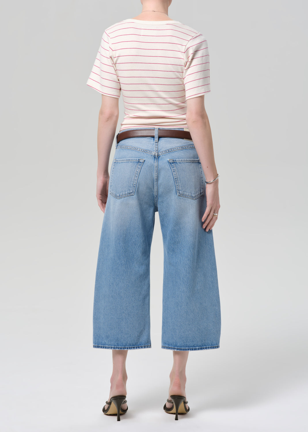 Person wearing a striped shirt and light blue jeans on a plain background