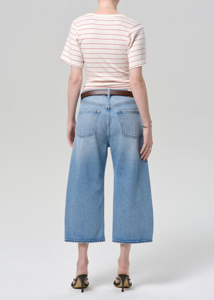 Person wearing a striped shirt and light blue jeans on a plain background