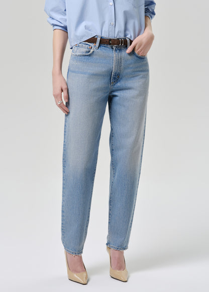 Person wearing light blue jeans and a light blue shirt on a grey background