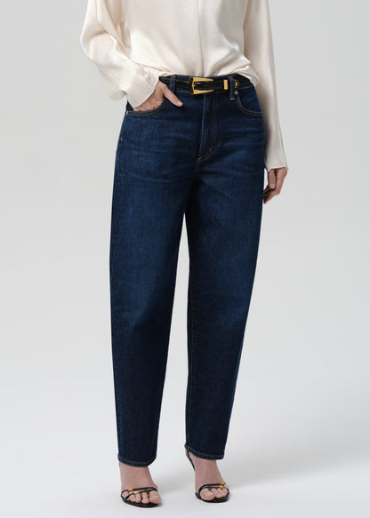 Person wearing dark blue jeans and a white shirt on a grey background