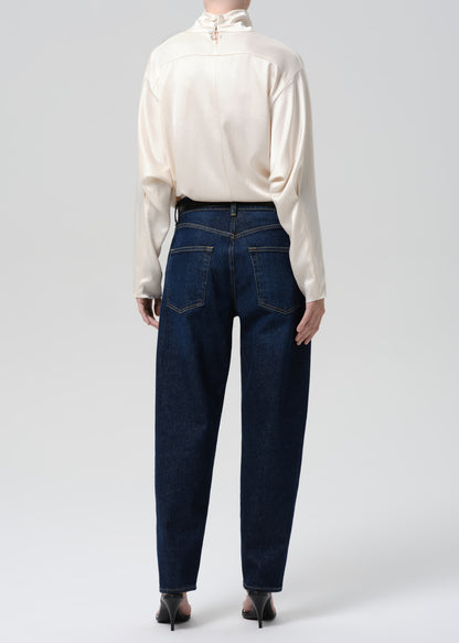 Person wearing a white blouse and dark blue jeans on a grey background
