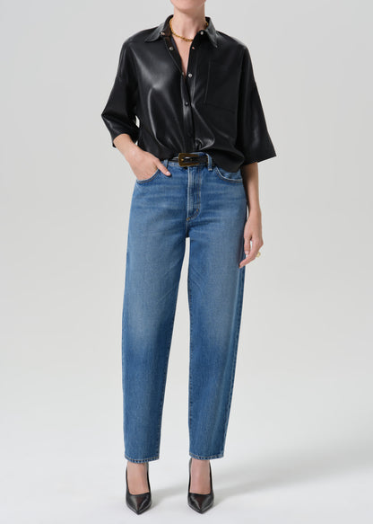 Person wearing black shirt with blue jeans on a grey background