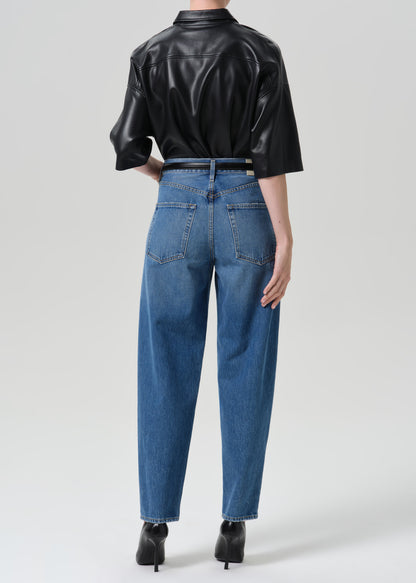 Person wearing black shirt with blue jeans on a grey background