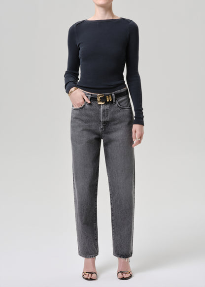 Model wearing a grey long sleeve top paired with washed black tapered jean