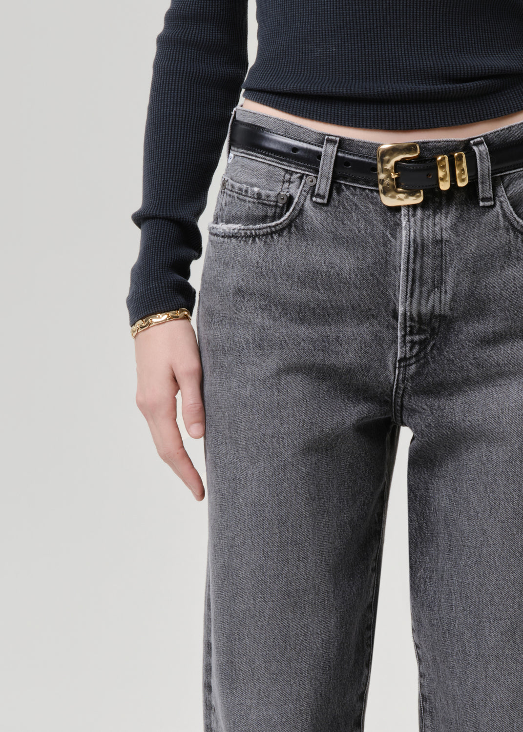 Model wearing a grey long sleeve top paired with washed black tapered jean