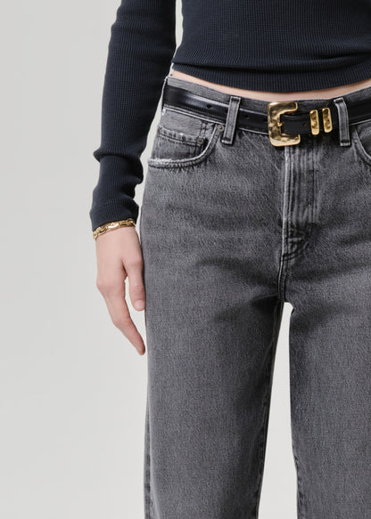 Model wearing a grey long sleeve top paired with washed black tapered jean