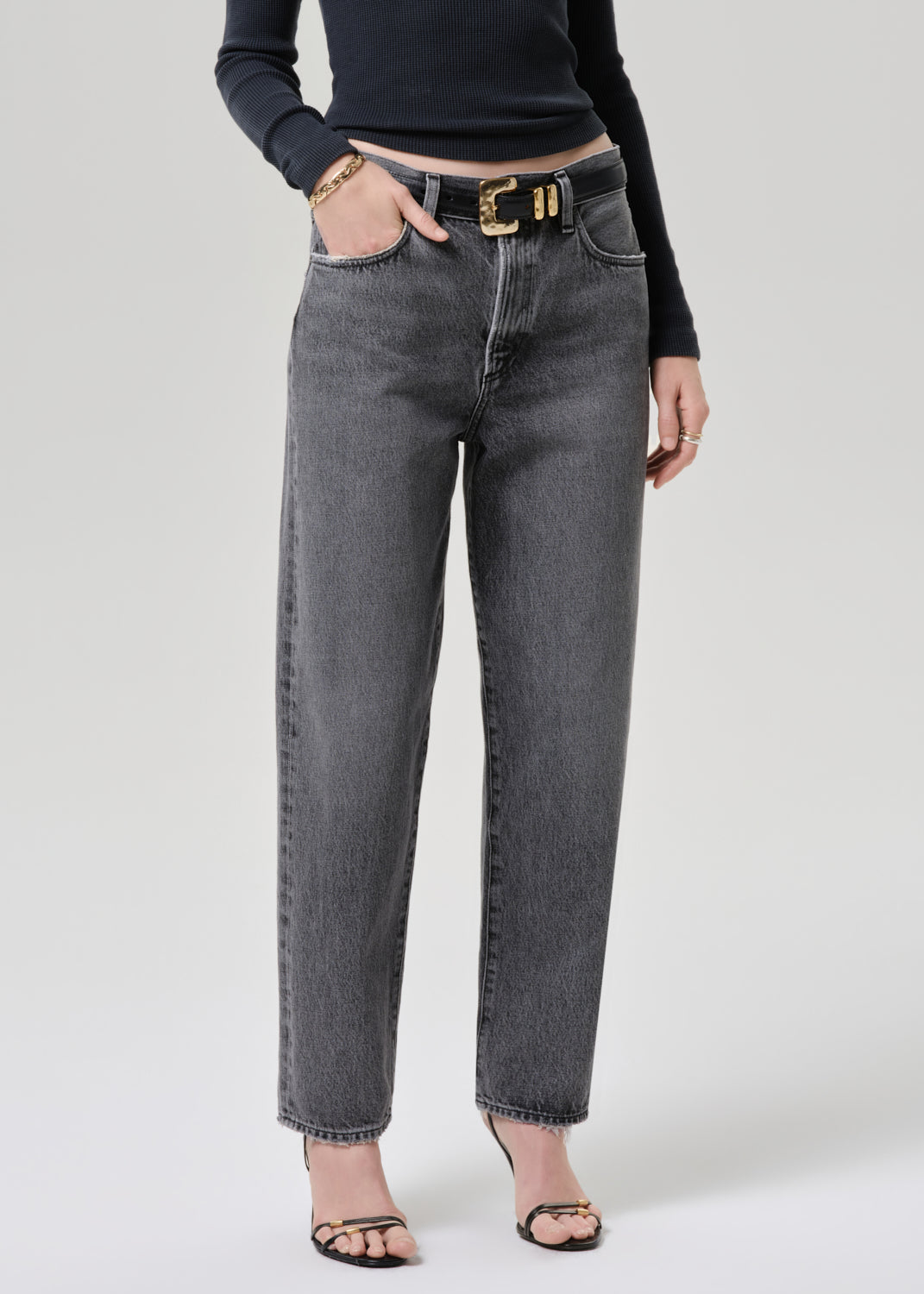 Model wearing a grey long sleeve top paired with washed black tapered jean
