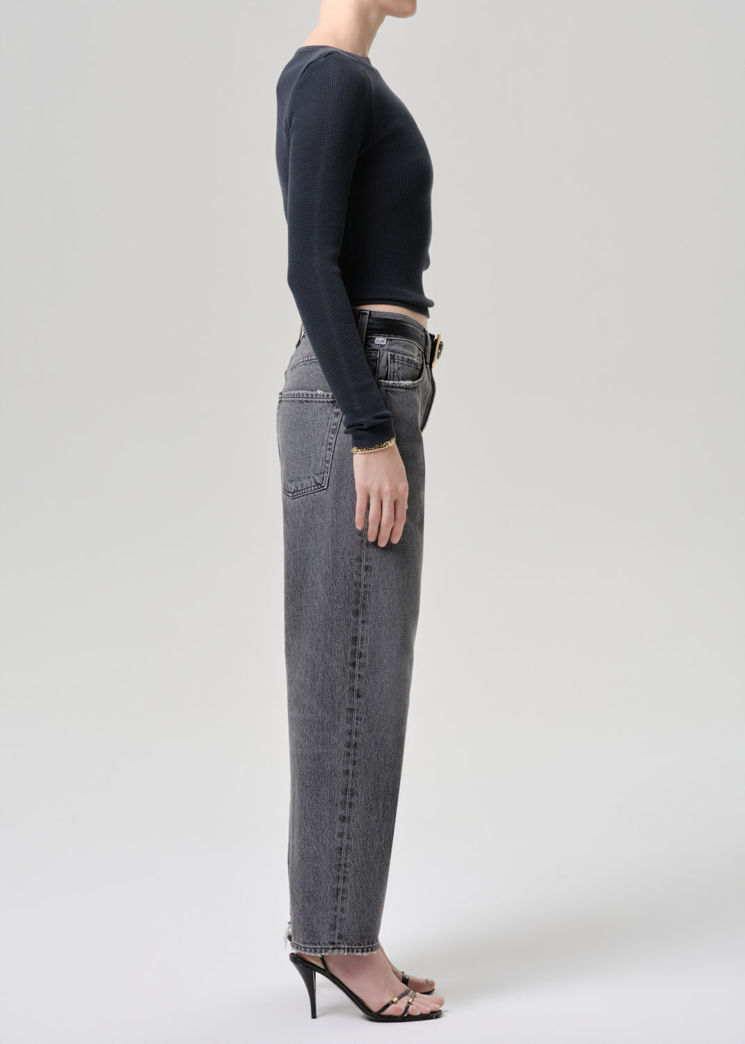 Model wearing a grey long sleeve top paired with washed black tapered jean