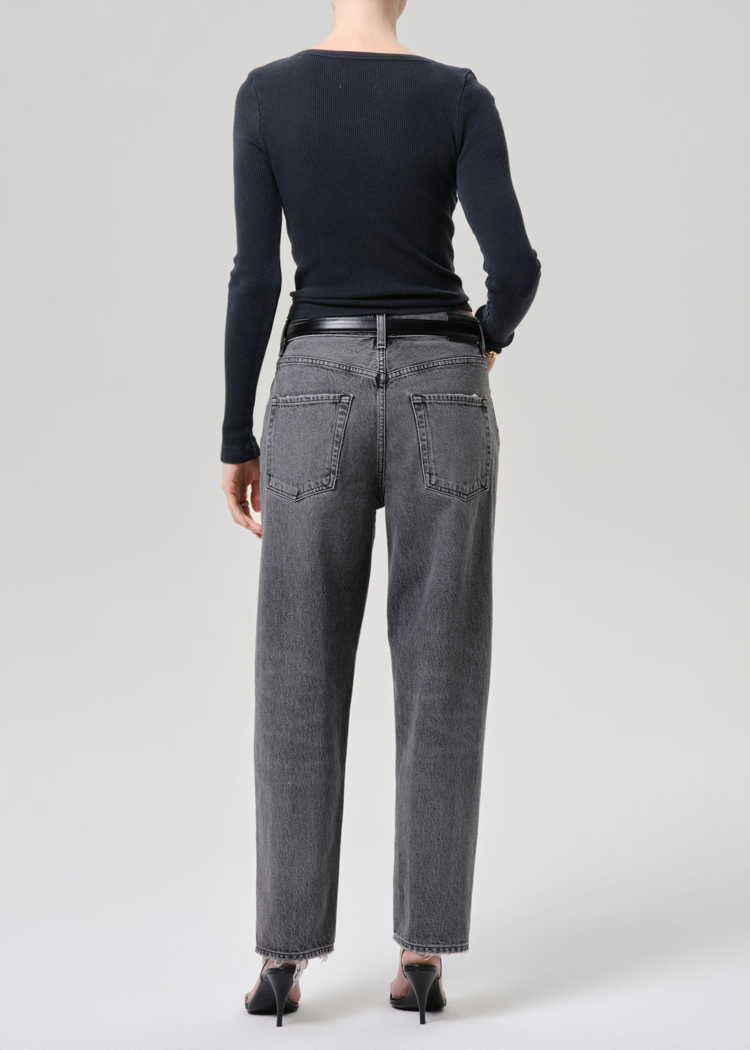 Model wearing a grey long sleeve top paired with washed black tapered jean