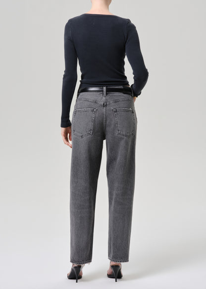 Model wearing a grey long sleeve top paired with washed black tapered jean