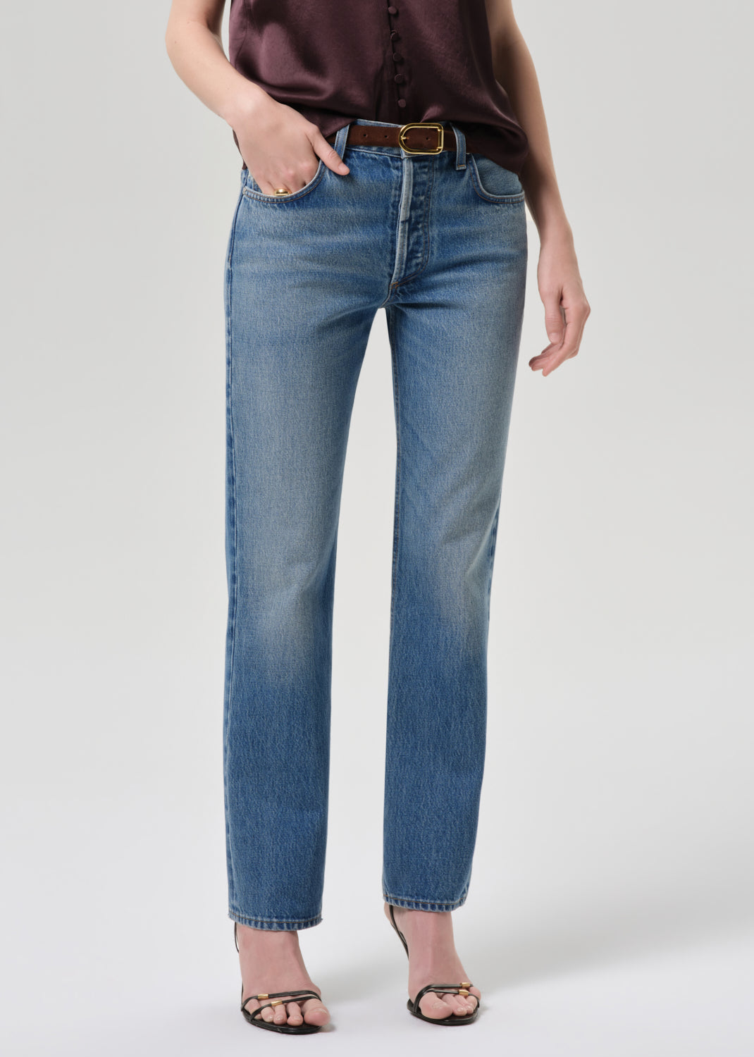 Person wearing blue jeans on a grey background