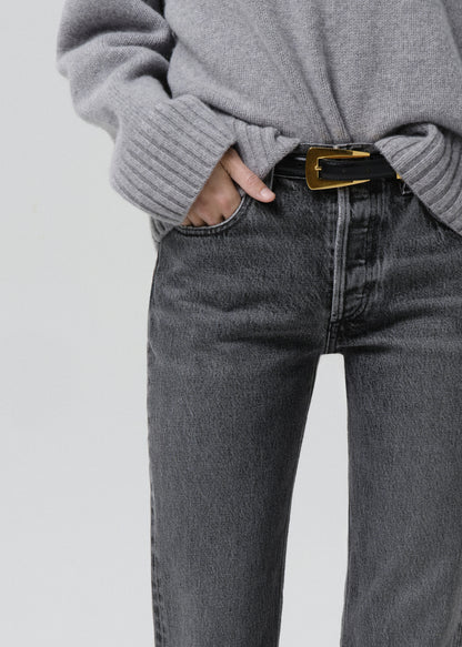 Close-up of grey straight leg jeans with a grey turtleneck sweater on a grey background