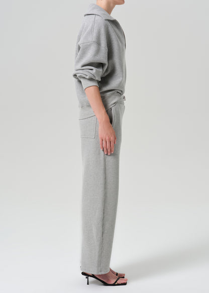 A model shown from the side wearing a light grey heathered sweatshirt and matching wide-leg sweatpants, paired with black heeled sandals, against a grey background.