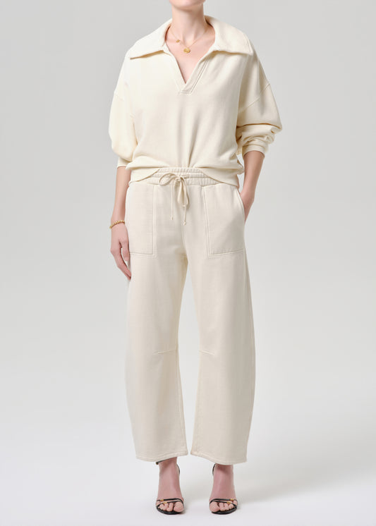 Person wearing a cream-colored outfit with a matching top and pants on a grey background