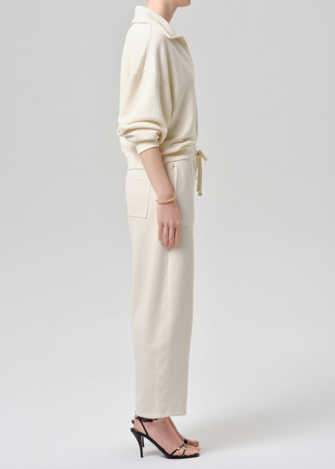 Person wearing a cream-colored outfit on a grey background
