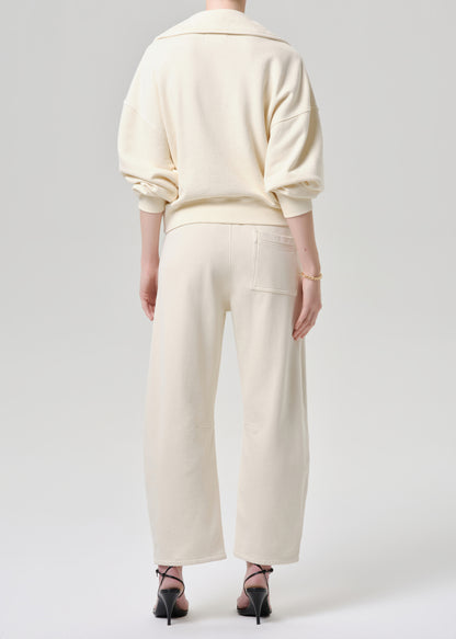 Person wearing a cream-colored outfit on a grey background
