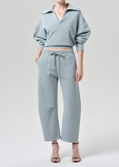 Person wearing a light blue outfit with a matching top and pants on a grey background