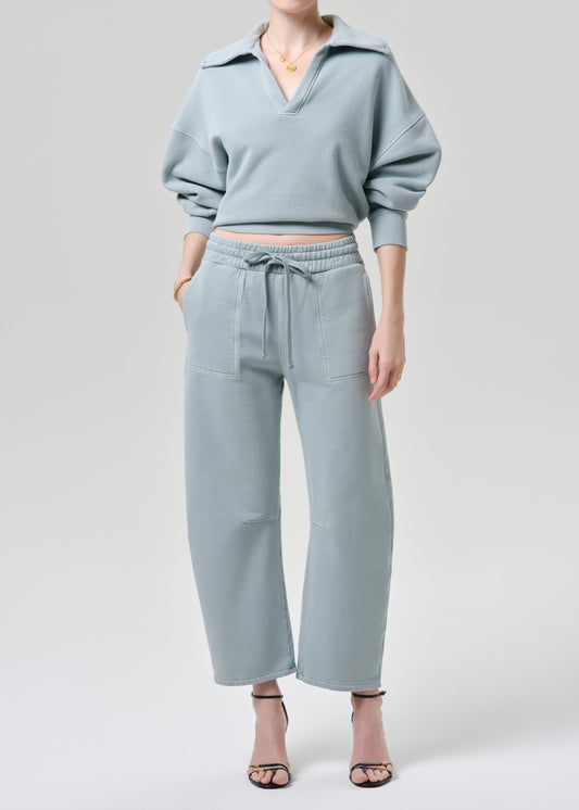 Person wearing a light blue outfit with a matching top and pants on a grey background