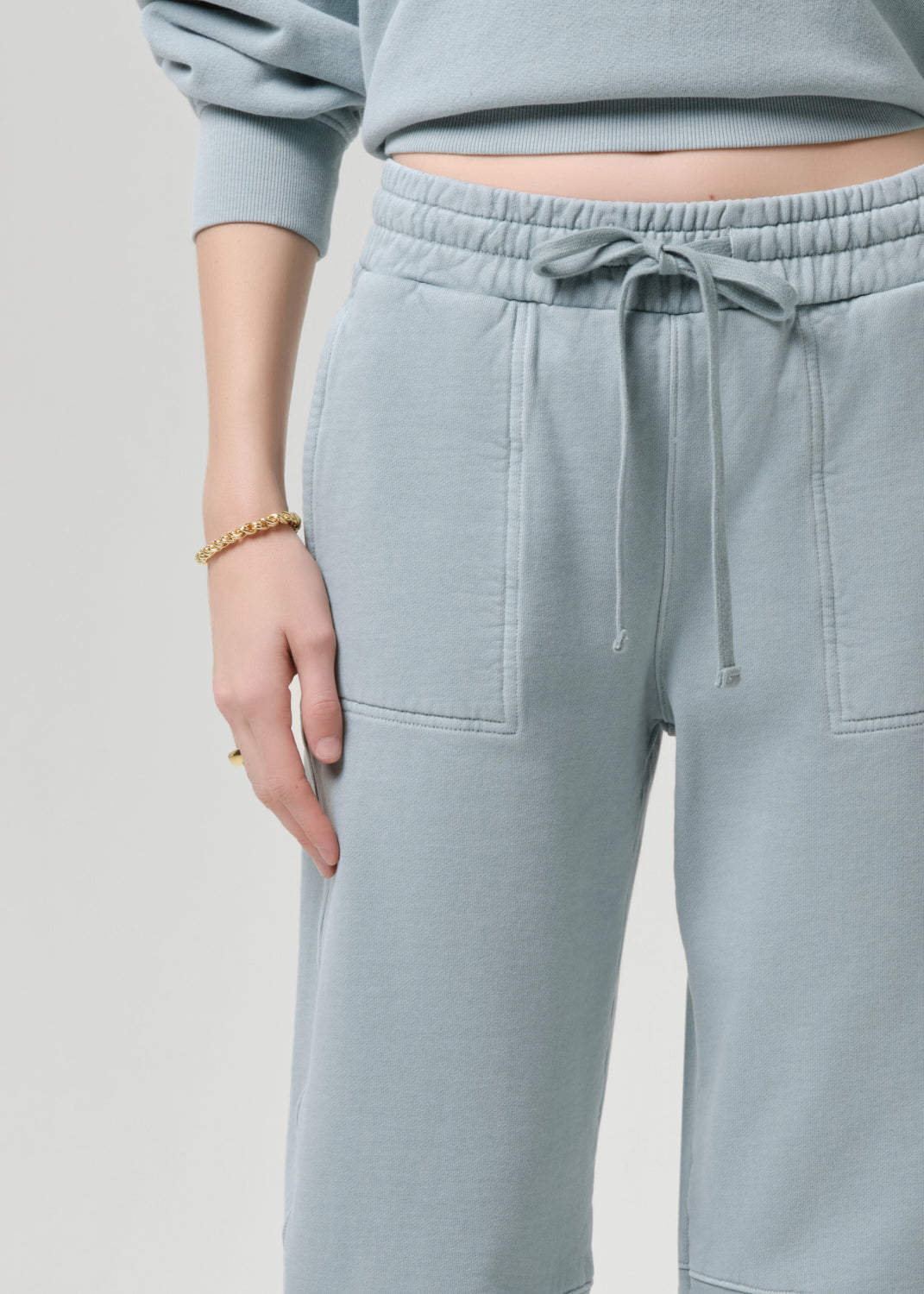 Light blue sweatpants with a drawstring on a grey background