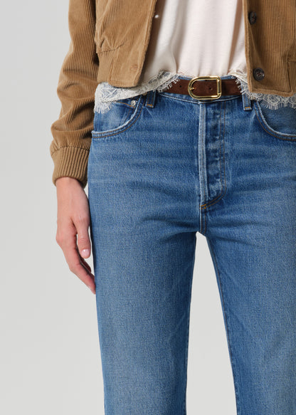 Close up of blue jeans and brown belt on a grey background