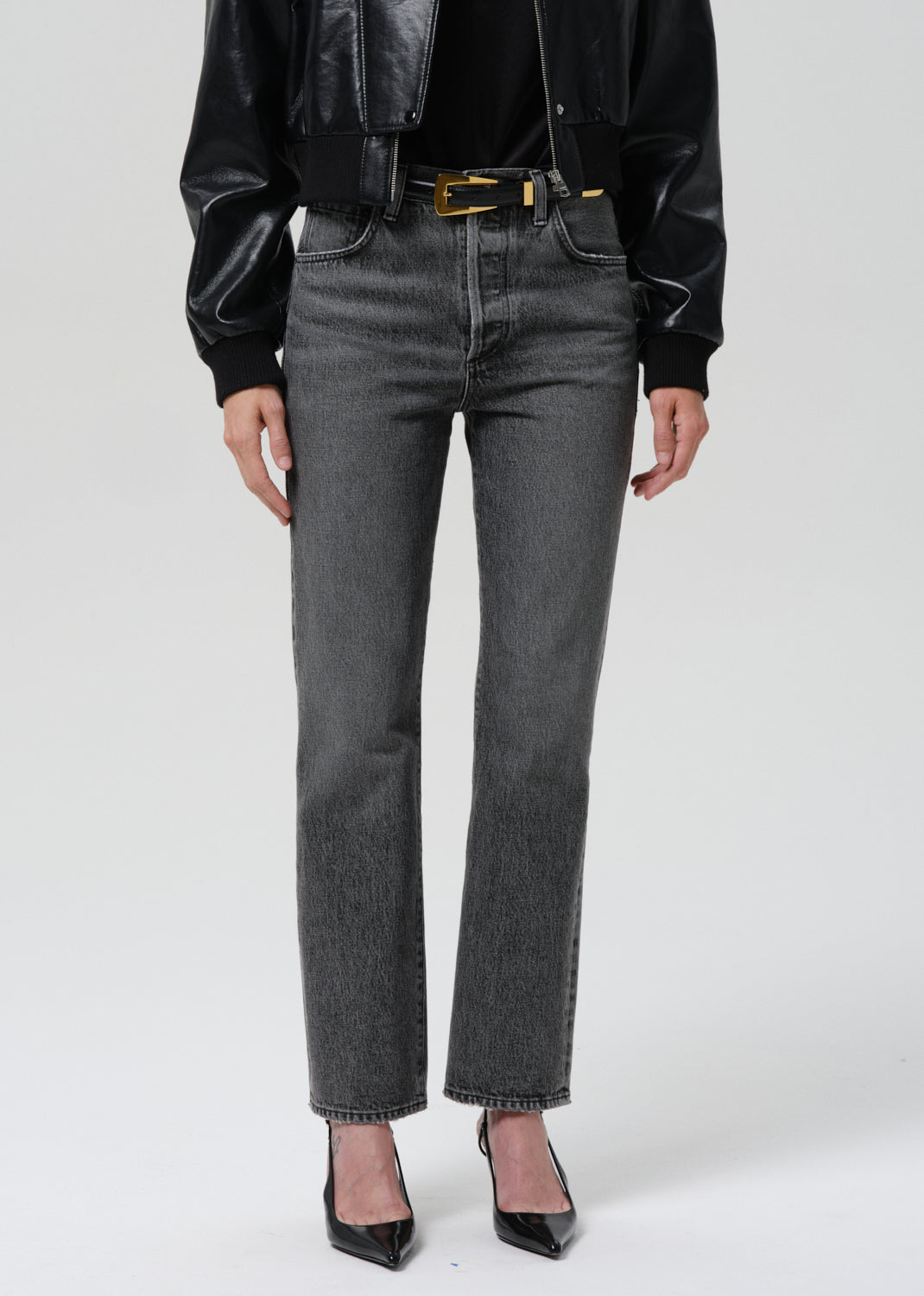 Person wearing black leather jacket, black shirt, and gray jeans on a grey background