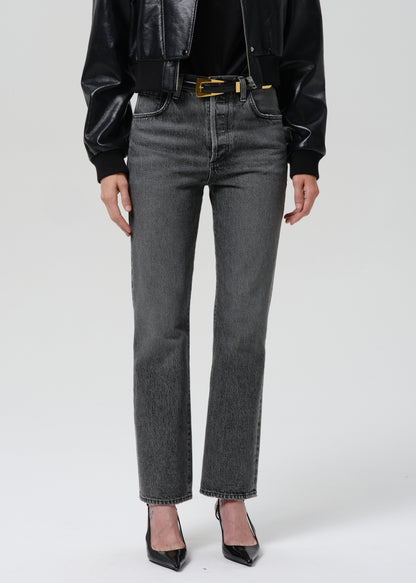 Person wearing black leather jacket, black shirt, and gray jeans on a grey background