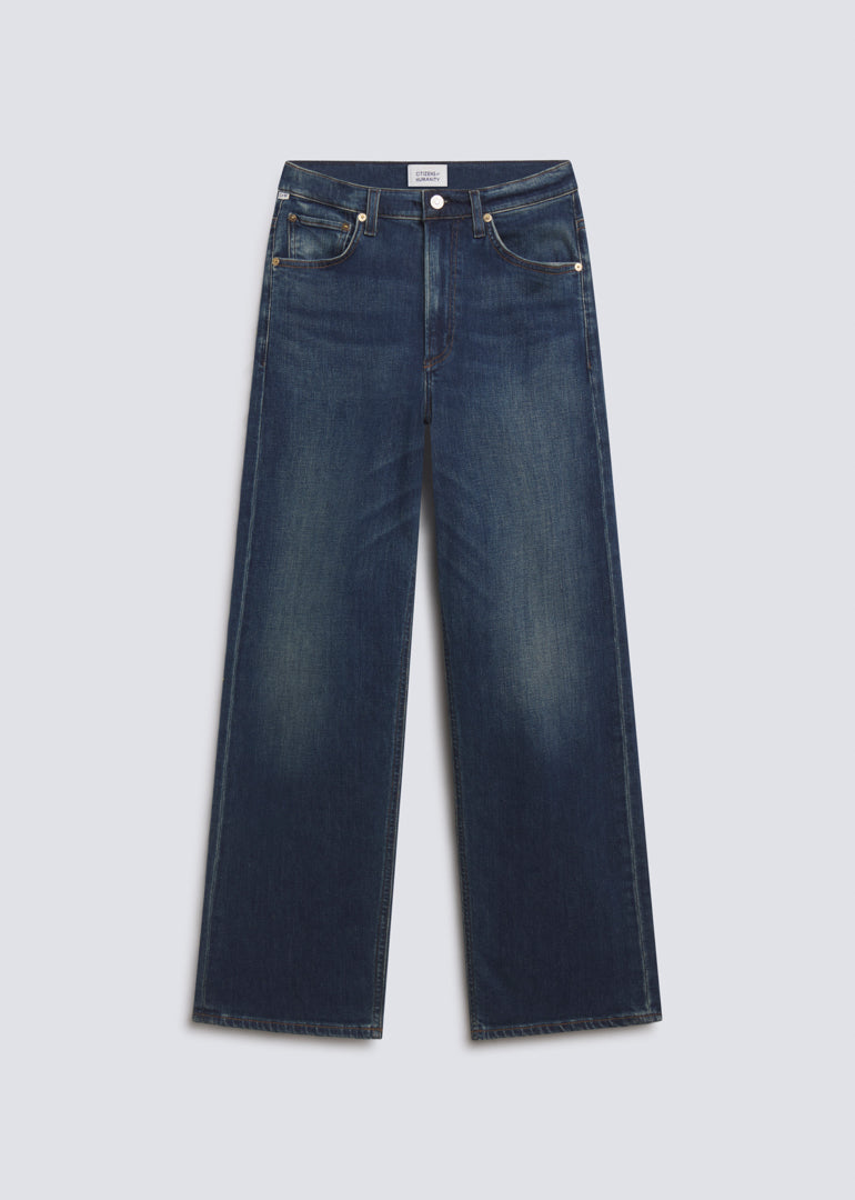 Palma Long in Pierre, featuring dark indigo denim with subtle fading, a relaxed wide leg silhouette, classic five-pocket design, and full-length fit, front view on a grey background.