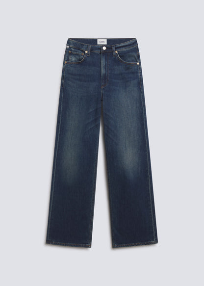 Palma Long in Pierre, featuring dark indigo denim with subtle fading, a relaxed wide leg silhouette, classic five-pocket design, and full-length fit, front view on a grey background.