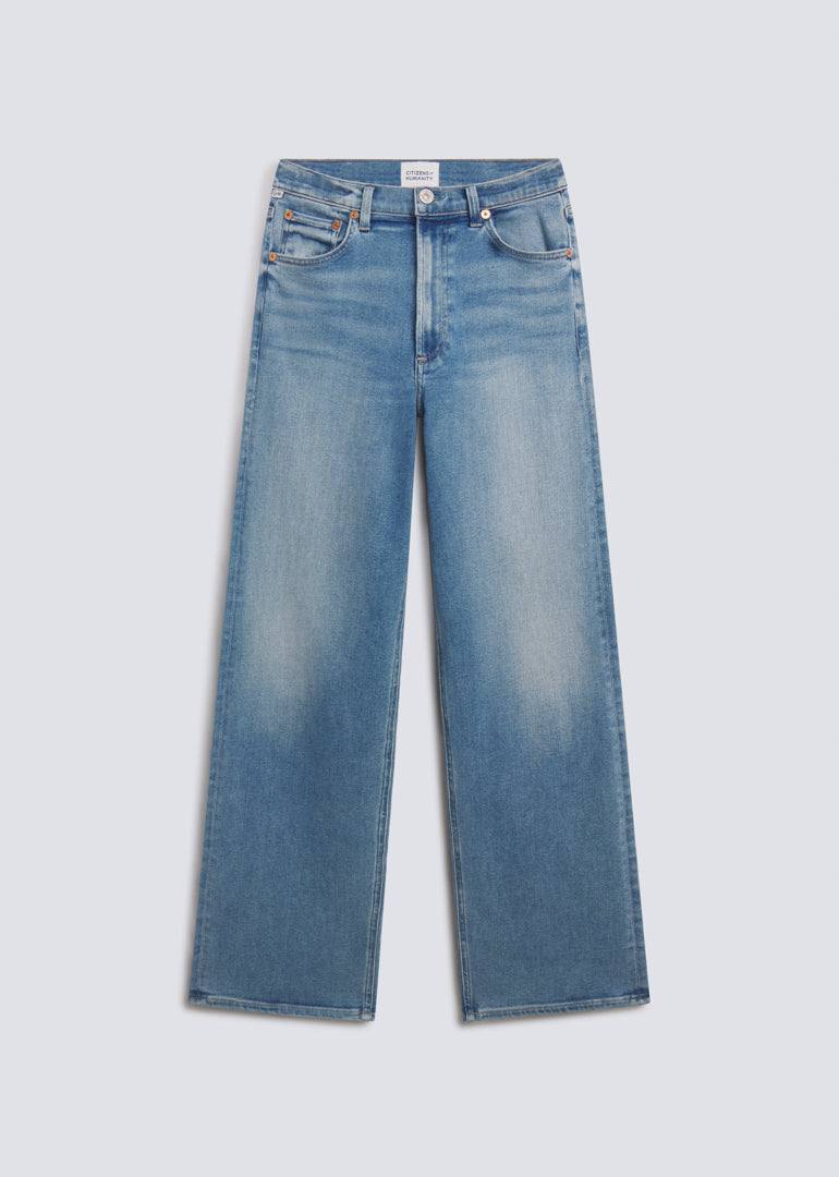 Palma Long in Celeste, featuring light blue denim with soft fading, a relaxed wide leg silhouette, classic five-pocket design, and full-length fit, front view on a grey background.
