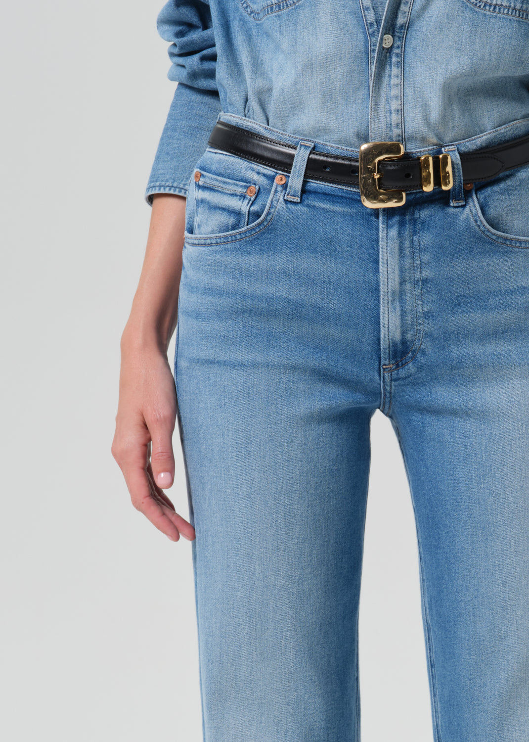 Close-up of light blue straight leg jeans on a grey background