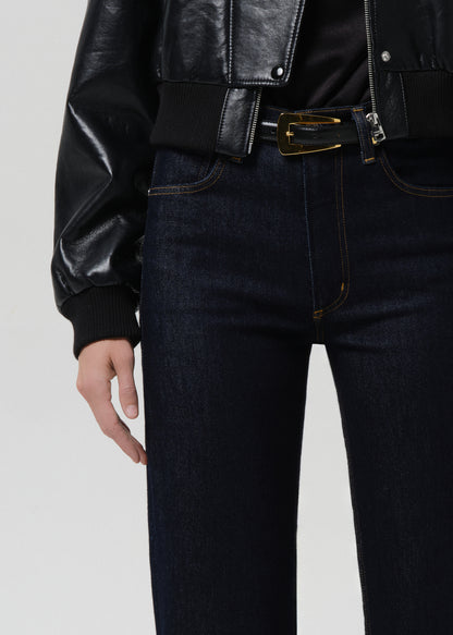 Person wearing a black leather jacket and dark jeans on a grey background