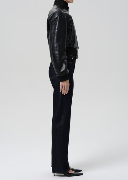 Person wearing a black leather jacket and pants on a grey background