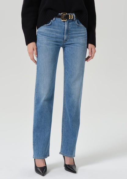 Person wearing a black crewneck sweater with light wash straight leg jeans on a grey background