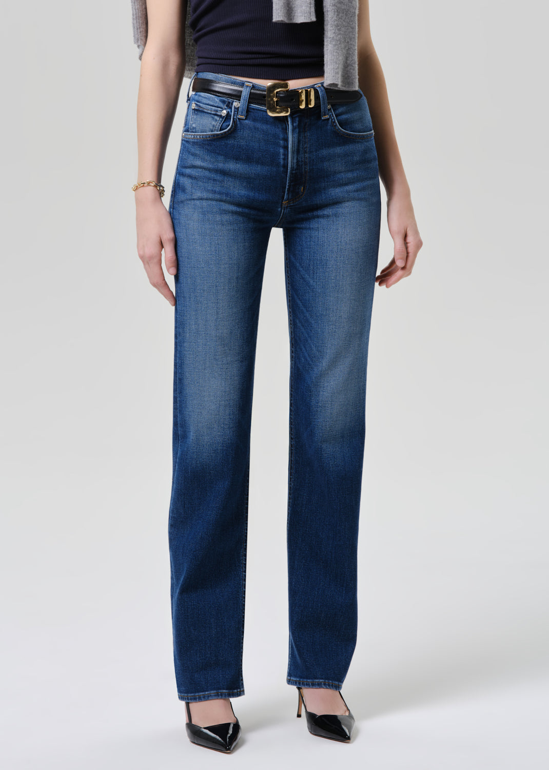 Person wearing blue jeans with a grey background