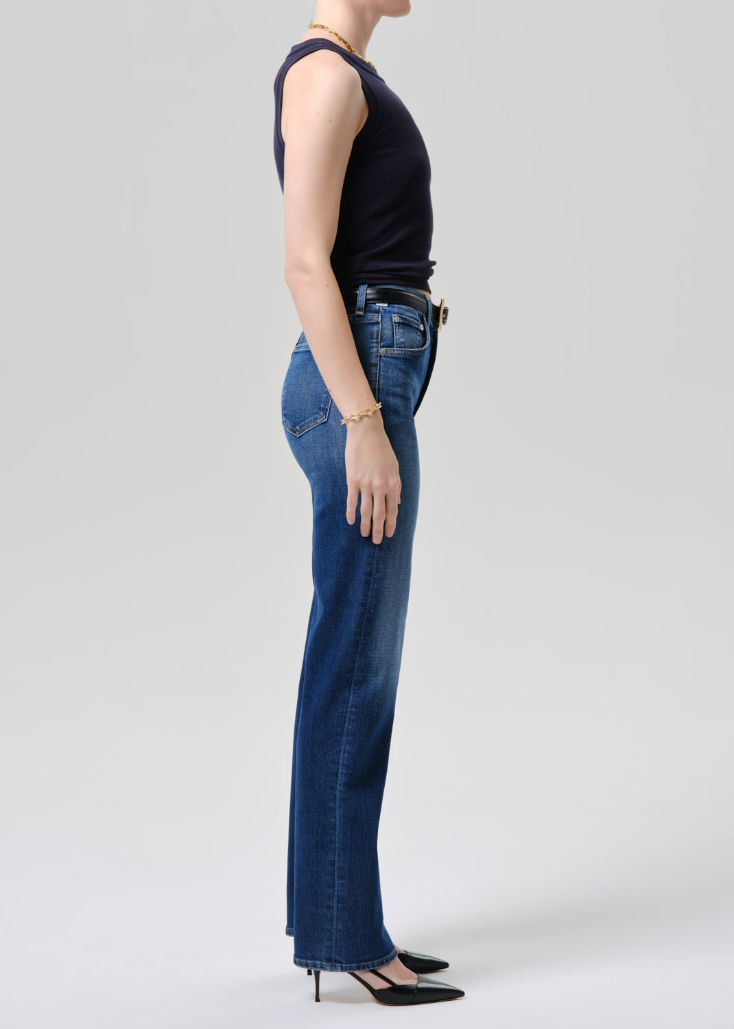 Person wearing blue jeans and a dark top on a grey background