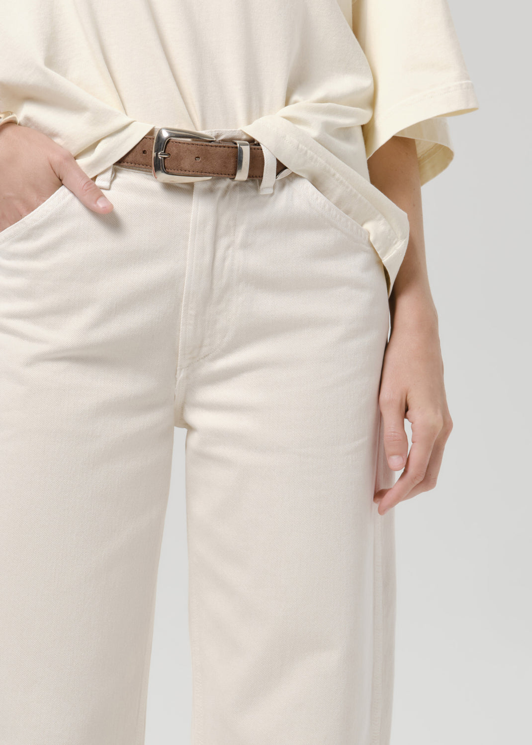 Close up of person wearing white pants on a grey background